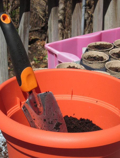 A trowel in an orange pot of dirt.
