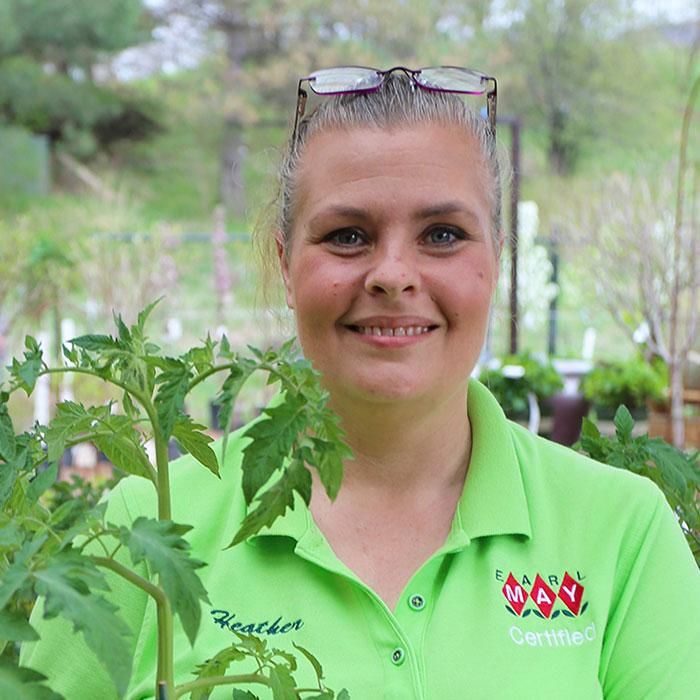 Portrait of an Earl May manager holding a tomato plant.